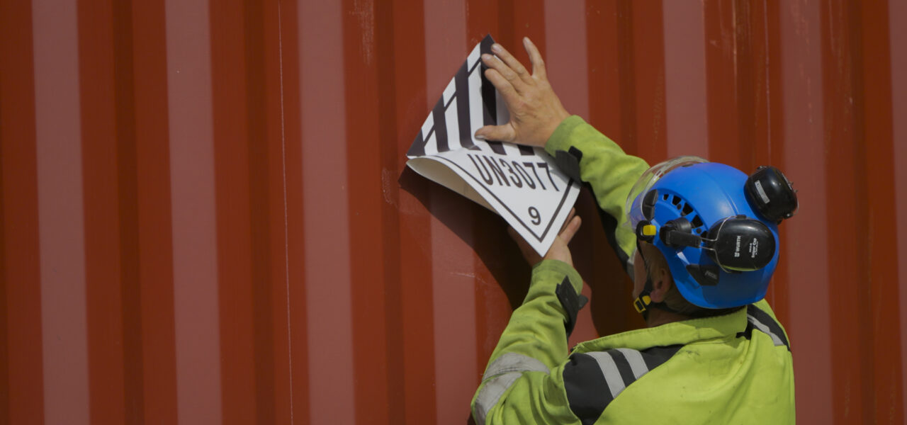 Applying a dangerous goods label to a shipping container during cargo handling operations at Hacklin Hamiko in HaminaKotka, Finland.